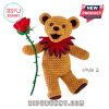 Orange crochet bear with red collar holding a rose.