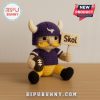 Crochet Viking football doll holding Skol sign and football on wooden background.
