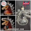 Three Godzilla shaped liquor bottles: two filled with amber liquid, one empty clear glass.