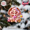 Pink-haired mermaid ornament sitting inside seashell with fish.