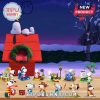 Multiple Snoopy figurines in different costumes and activities displayed in front of red doghouse with wreath.