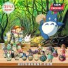 Totoro character figurines arranged in front of a forest background.