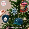 Seattle Mariners ornaments, including a baseball glove, cap, and snowflake, hanging on a Christmas tree.