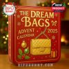 The Dream Bags Advent Calendar box stands on a wooden table near a Christmas tree, featuring gold embossed lettering and a golden handbag image symbolizing fashion and festivity!