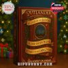 The advent calendar has a vintage book appearance with a textured red cover, golden foil details, and Outlander-themed quotes. The centerpiece depicts standing stones surrounded by seasonal foliage!