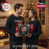 Couple in Rolling Stones sweaters holding the band’s advent calendar in a festive room.