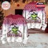 Pair of front and back Grinch Cardinals Christmas sweaters in a holiday setting.