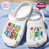 Angled shot of cartoon-themed white Crocs with autism slogan design, lying on a soft blue surface!