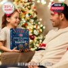 A child gives a Chicago Cubs 2025 Advent Calendar to an adult near a decorated Christmas tree.
