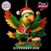 A festive green parrot with a red Santa outfit poses happily next to a small Christmas tree and toy drum, with a golden loop for hanging as an ornament!