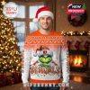 Cincinnati Bengals ugly Christmas sweater with the Grinch and team logo, featuring orange top, white bottom, and holiday decorations, worn by a smiling man in a cozy Christmas room!