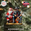 An ornament of Hank Williams Jr. with Santa Claus, both holding guitars, hanging on a decorated Christmas tree.