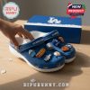 Close-up of blue Dodgers clogs with sports charms and branded box in background.