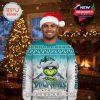 A man wearing a festive sweater with a Grinch and Miami Dolphins theme, standing in a holiday-decorated living room with a Christmas tree and fireplace!