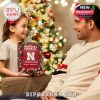 Joyful scene of a child presenting a Nebraska Football advent calendar as a gift to her dad by the Christmas tree!