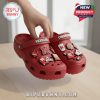 Hand lifting Nebraska Cornhuskers Crocs with team-themed charms on table!