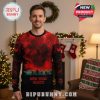Man wearing New York Giants and Stranger Things crossover Christmas sweater near decorated tree and fireplace.