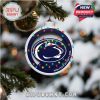 A close-up of a Penn State Christmas tree ornament, accented with festive multicolor lights and school branding, hung on a snow-dusted tree!