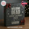 Front view of The Walking Dead Advent Calendar 2025 box with silver holiday motifs and red ribbon on a wooden surface!