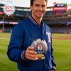 Man in Texas Rangers jacket at a stadium holding a whiskey glass with baseball stitching and logo design.