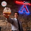 Man raising an Arizona Diamondbacks whiskey glass with team logo sign in the background!