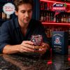 Man in bar holding Arizona Wildcats whiskey glass with red drink and limited edition box on marble counter!