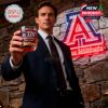 Man in suit raising Arizona Wildcats anniversary whiskey glass in front of neon A logo and stone wall backdrop!