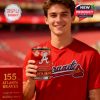 A young Atlanta Braves fan stands in the stadium holding a red themed anniversary whiskey glass with a matching display box nearby!