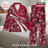Custom Atlanta Falcons pajamas laid out on a bed with bold red design, floral patterns, and personalized name option!
