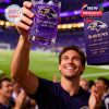 Fan raising Ravens 30th Anniversary purple whiskey glass proudly under stadium lights in front of cheering crowd!
