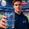 Young fan presenting a Buffalo Bills commemorative whiskey glass at the stadium with crowd and lights in the background.