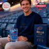 Fan sitting in stadium seats with Buffalo Bills whiskey glass and matching commemorative box, celebrating the team's 65-year legacy.