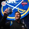 A confident fan lifting a Buffalo Sabres commemorative whiskey glass beneath iconic team imagery!