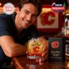 A close view of a happy fan presenting a Calgary Flames whiskey glass on a bar counter!