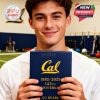 A smiling young man holds a Cal-branded whiskey glass box celebrating the 143rd anniversary, standing in a gym setting!