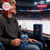 Fan seated at hockey arena holding 54th anniversary Carolina Hurricanes glass and gift box nearby during a live game!