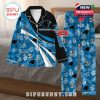 Blue and black Carolina Panthers pajamas placed on a bed, featuring team graphics, white floral patterns, and name personalization!