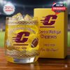 A college themed whiskey glass with Central Michigan Chippewas branding and decorative patterns sits beside a matching yellow box!