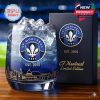 A stylish glass celebrating CF Montréal with a frosted blue drink and detailed etching of the city's skyline beneath the team crest, shown beside a dark navy gift box labeled EST. 2010!