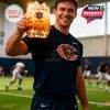 Chicago Bears anniversary whiskey glass resting in hand with gold skyline and bear logo design, held by a fan seated in a stadium row before kickoff!