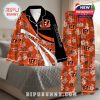 Cincinnati Bengals-themed pajamas on a bed, designed with vibrant orange, floral patterns, and personalized fan name areas!