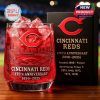 A Cincinnati Reds 135th Anniversary whiskey glass with ice cubes, featuring the team logo and an engraved stadium design.
