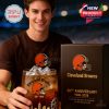 Cleveland Browns fan proudly presenting the anniversary whiskey glass and box while repping his team shirt in a stadium setting!