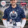 Man wearing an Edmonton Oilers and Bluey collaboration hoodie with team logo, cartoon characters, and paw print graphics in front of an arena.