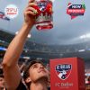 A person in a crowded soccer stadium raises a special edition FC Dallas whiskey glass toward the sky during a celebration!