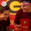 A fan duo smiles as they examine a special edition Georgia Bulldogs whiskey glass engraved with team pride and set against a vivid red and gold background!