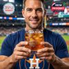 A happy fan grips the Houston Astros 60th anniversary glass, radiating excitement and team loyalty at the stadium!