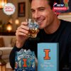 Man sipping drink from Illinois Fighting Illini whiskey glass in living room with gift box and school-themed decor in background!