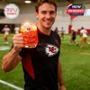 Person holding the Kansas City Chiefs whiskey glass at a training facility, celebrating the team’s 65th anniversary with the anniversary branding clearly displayed.