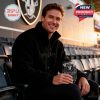 Smiling man sitting with Raiders whiskey glass inside stadium seating!